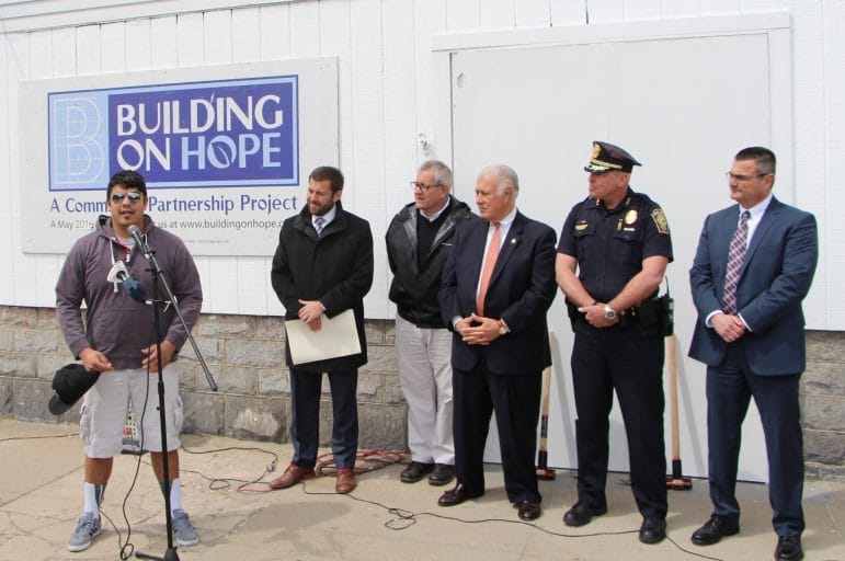 Gibran Ortiz-Perez (on the microphone), a former MPAL student who is still nvolved with the Michael Briggs Community Center, is joined by,from left, E.J. Powers (Building on Hope Steering Committee), Jonathan Halle (Building on Hope Co-Chair), Mayor Ted Gatsas, Chief Nick Willard and David Mara (Chairman of MPAL) .