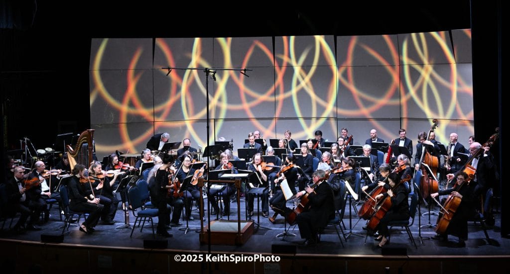 Image is a photo by keith spiro of concertmaster Juiri Yu preparing the orchestra moments before conductor Roger Kalia comes on stage.