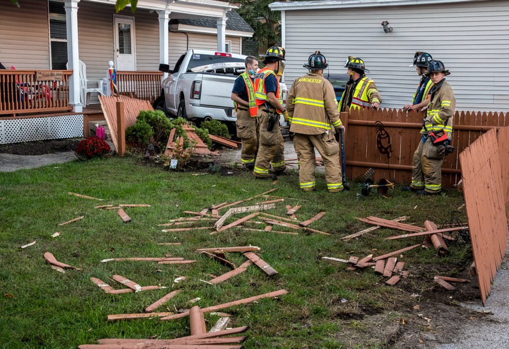 Truck swerves to avoid accident on Maple Street, crashes through fence, pushing parked car into garage post image